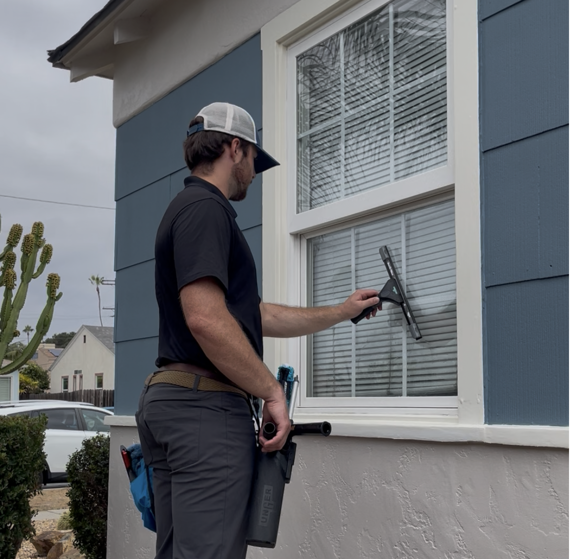 Evan cleaning exterior residential windows with a squeegee
